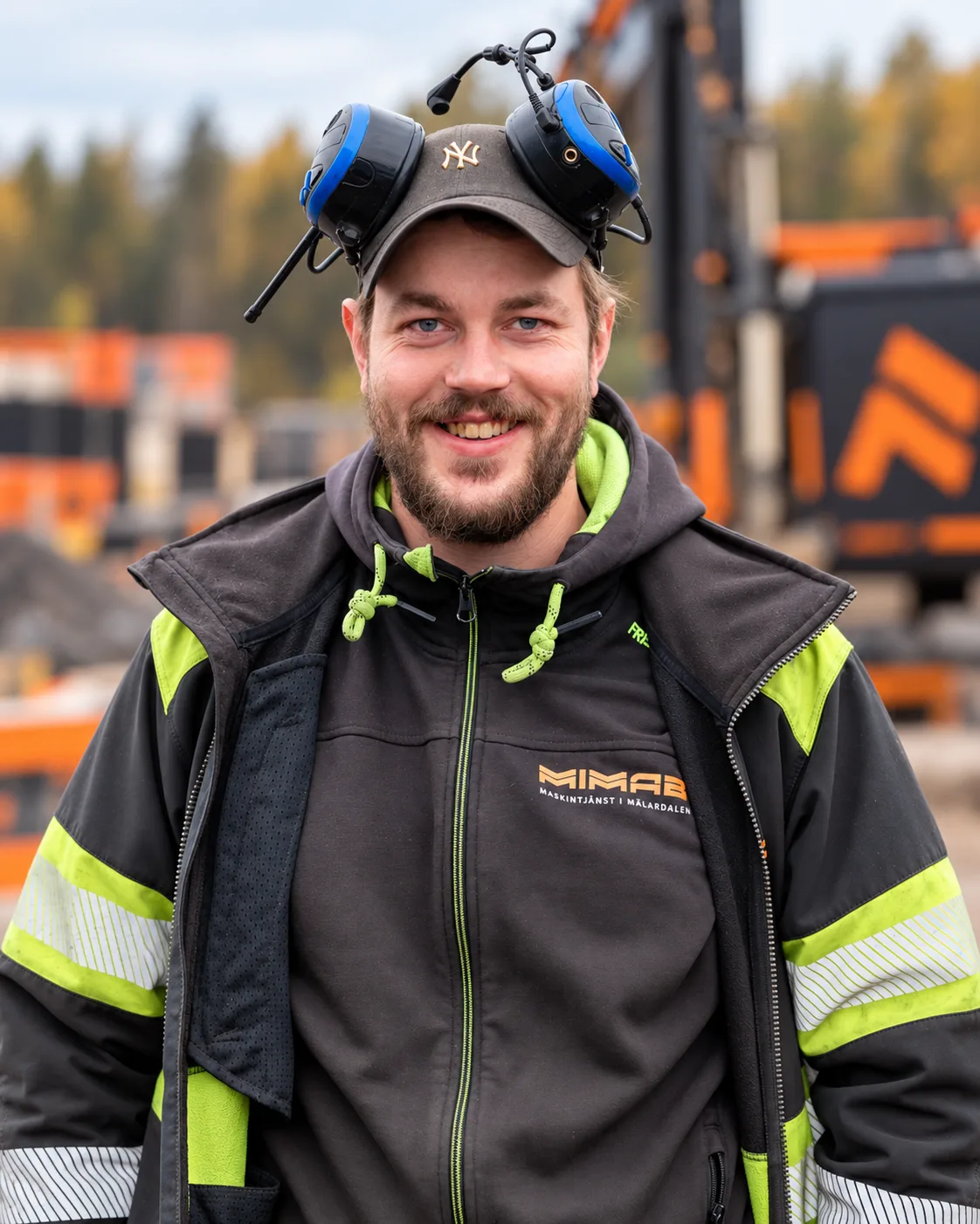 Jocke i varselkläder, keps och hörselkåpor på en byggarbetsplats
